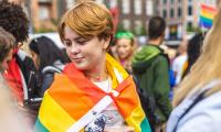 Ung kvinde indhyllet i regnbueflag